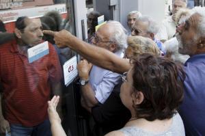 Pensioners waiting outside a closed National Bank branch and hoping to get their pensions, argue with a bank employee (L) in Iraklio on the island of Crete, Greece June 29, 2015. REUTERS/Stefanos Rapanis
